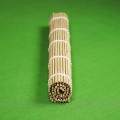 A bamboo sushi rolling mat is tightly rolled and secured with white string, placed on a vibrant green background, creating a simple and organized look.