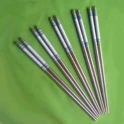 Five pairs of silver-colored chopsticks with decorative handles are arranged in a row on a green background.