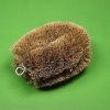 coconut tawashi cleaning brush with dense natural coir bristles and metal hanging loop on a green background
