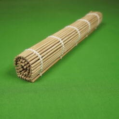 A bamboo sushi rolling mat is tightly rolled and secured with white string, placed on a vibrant green background, creating a simple and organized look.
