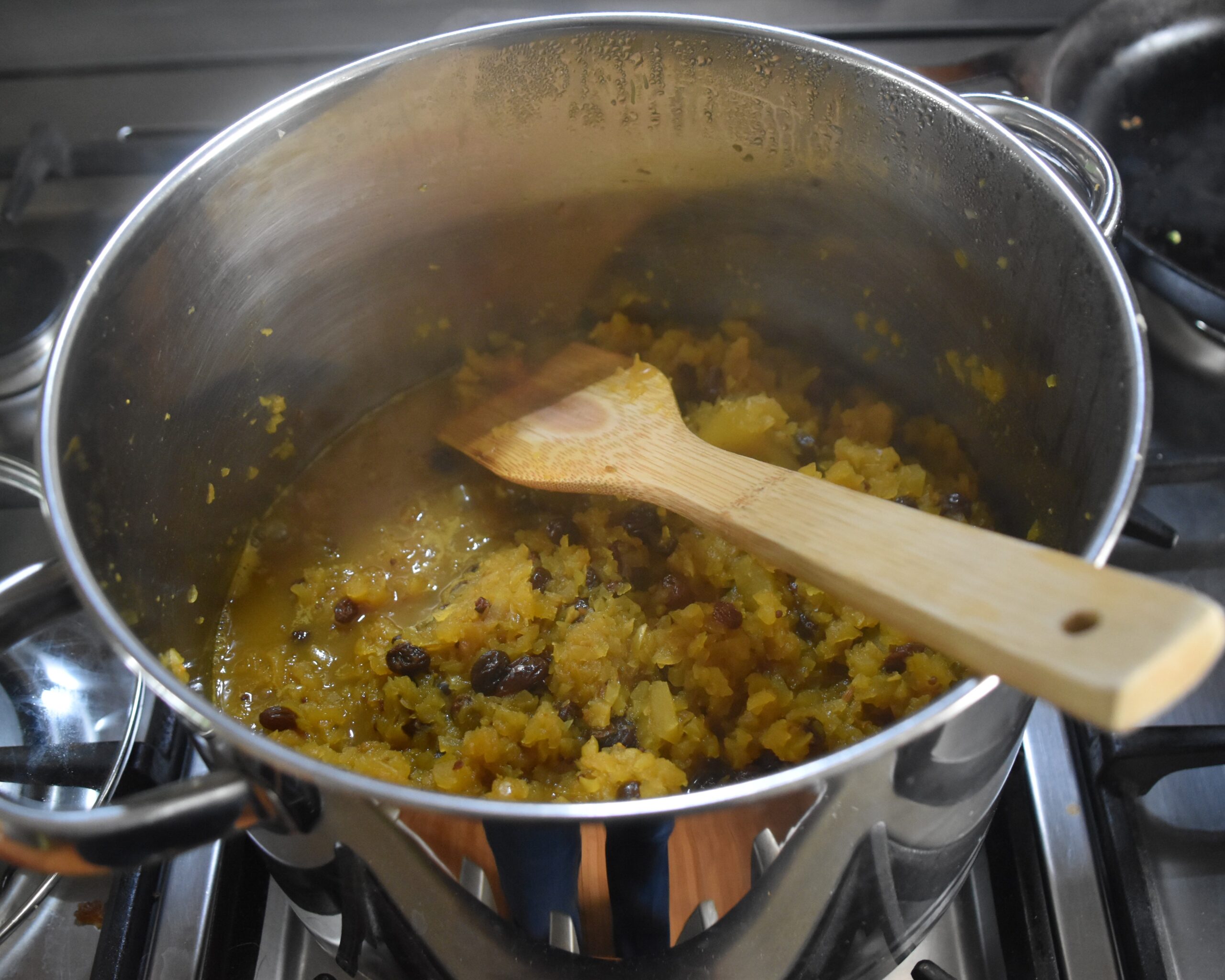 Image of a cooking pot with marrow pickle and a bamboo spatula.