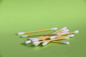 Close up of bamboo plastic free cotton buds with white cotton tips on green background