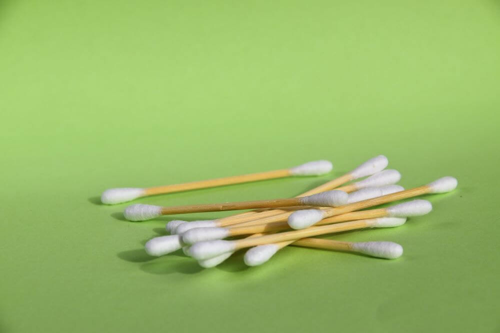 Close up of bamboo plastic free cotton buds with white cotton tips on green background