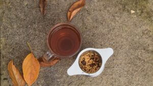 image of a cup of rosehip tea, with the ground rosehips in a cup infuser next to it