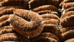 pile of coconut tawashi cleaning brushes with dense brown coir bristles and metal hanging loops