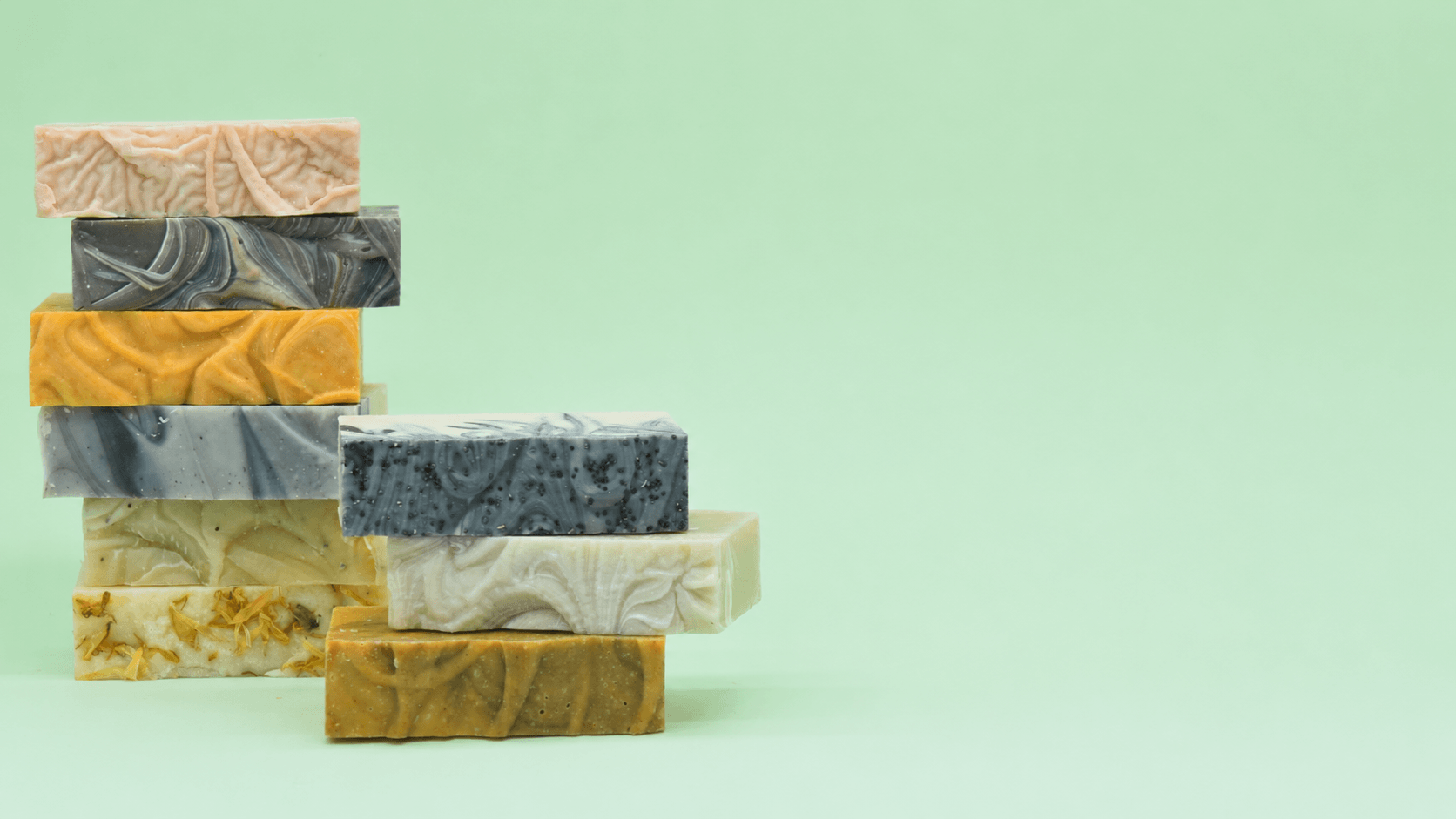 Selection of Uno handmade soap bars stacked on the left against a pale mint-green background