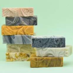 Selection of colourful Uno handmade soap bars stacked against a pale green background