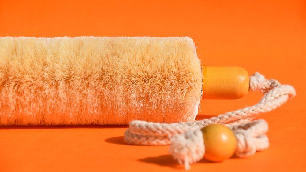 Image of a sisal back brush with rope, showing one end and its rope in detail, against an orange background.