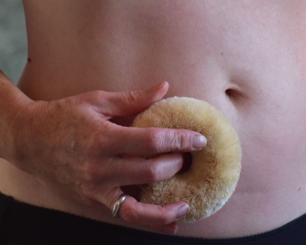 Image of a sisal body brush dry brushing a belly
